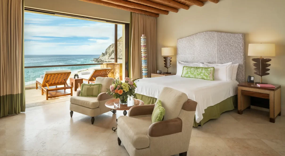 Elegant oceanfront room with wood beams, lounge balcony, and serene coastal views.